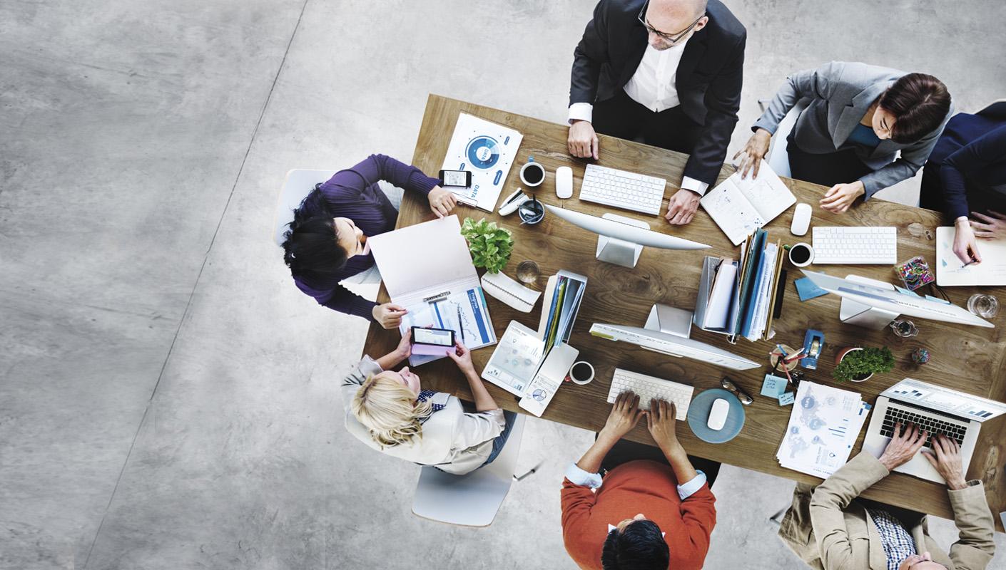 top down view of a group of people working at a busy communal desk