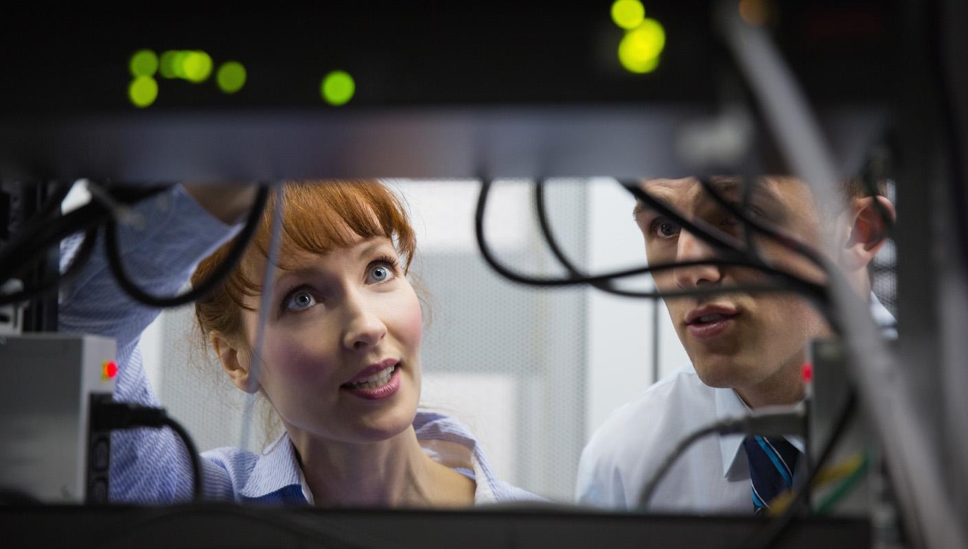 A view from the other side of a server rack where we can see two people examining the machines.