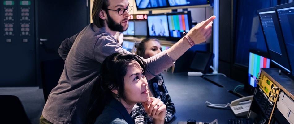 People in a control room reviewing playback monitors.